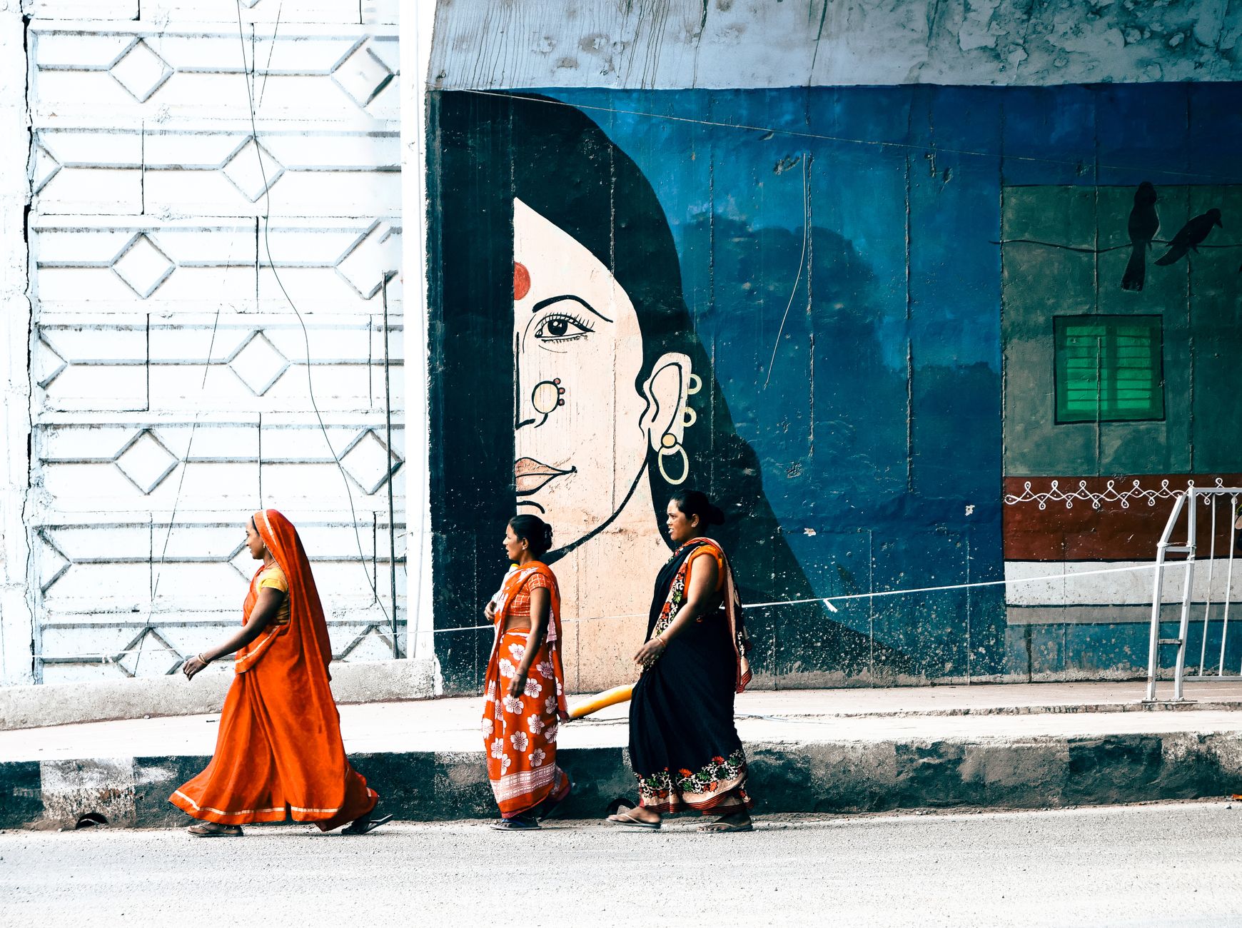 Indian women walking in front of a graffiti image
